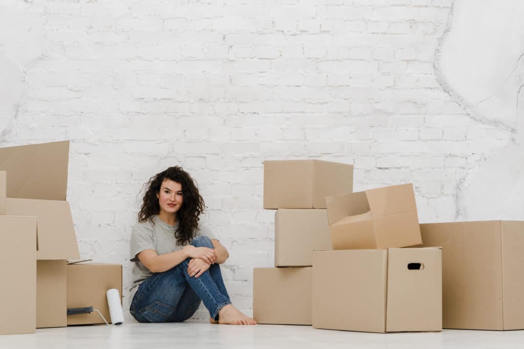 Smiling woman sitting on the floor between stacks of moving boxes